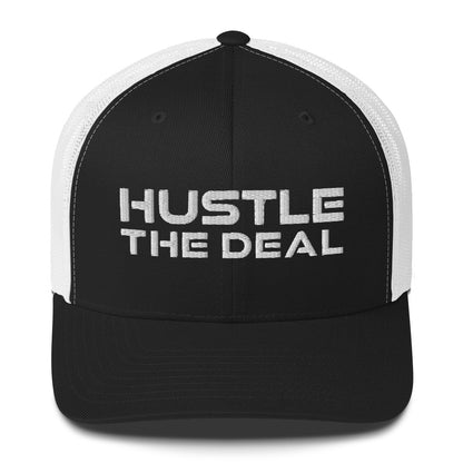 Black and white trucker hat with embroidered Hustle The Deal logo
